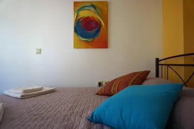 a bedroom with a bed with a painting on the wall at Cosy guest house with private yard in Saronida
