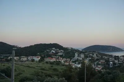 a town on a hill next to a body of water at Cosy guest house with private yard in Saronida