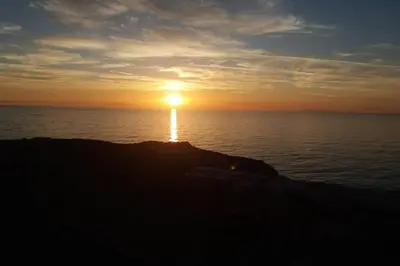 a sunset over the ocean with the sun on the horizon at Cosy guest house with private yard in Saronida