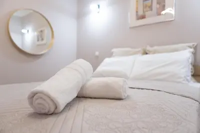 a white bed with a rolled up towel on it at Plato's Square Apartments in Athens