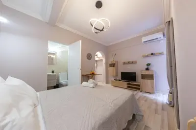 a bedroom with a white bed and a bathroom at Plato's Square Apartments in Athens