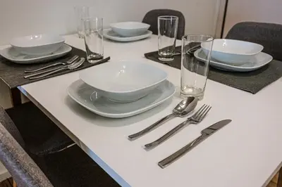 a table with white plates and silverware on it at Modern 5BD Apartment in the Heart of Athens in Athens