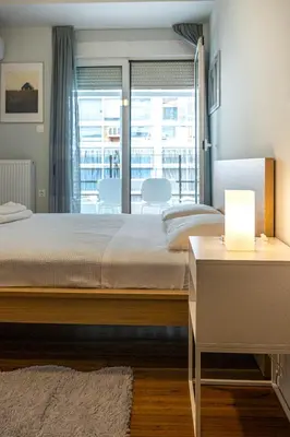 a bedroom with a large bed and a table with a lamp at Modern 5BD Apartment in the Heart of Athens in Athens