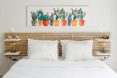 a bed with white pillows and a wooden headboard with cactuses at Koukaki Studio with a Sunny Balcony, near the Acropolis in Athens