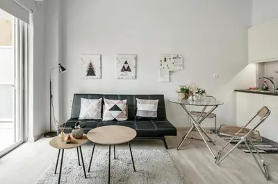 a living room with a black couch and a table at Koukaki Studio with a Sunny Balcony, near the Acropolis in Athens