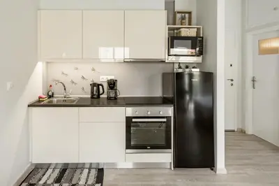a kitchen with white cabinets and a black refrigerator at Koukaki Studio with a Sunny Balcony, near the Acropolis in Athens