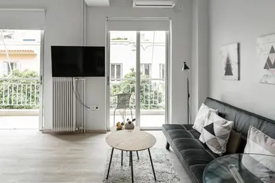 a living room with a black couch and a table at Koukaki Studio with a Sunny Balcony, near the Acropolis in Athens