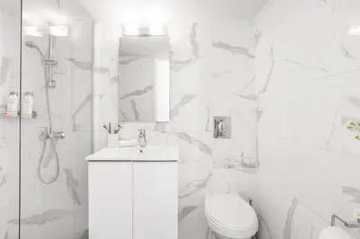 a white bathroom with a toilet and a shower at Koukaki Studio with a Sunny Balcony, near the Acropolis in Athens