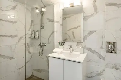 a white bathroom with a sink and a shower at Koukaki Studio with a Sunny Balcony, near the Acropolis in Athens