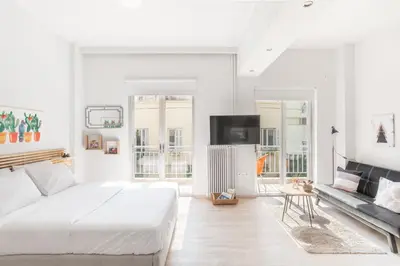 a white bedroom with a large bed and a couch at Koukaki Studio with a Sunny Balcony, near the Acropolis in Athens