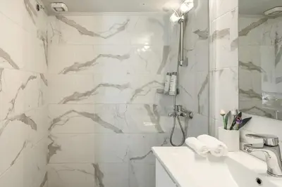 a white bathroom with a shower and a sink at Koukaki Studio with a Sunny Balcony, near the Acropolis in Athens
