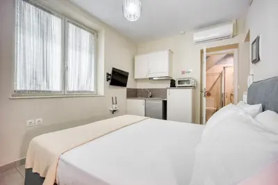 a bedroom with a white bed and a kitchen at Bentzi...Boutique Apartment 1, Classic Double with kitchenette, 2 Guests in Athens