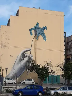a mural on the side of a building with a hand holding a flower at Paris & Helen in Athens
