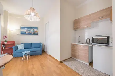 a living room with a blue couch and a kitchen at Paris & Helen in Athens