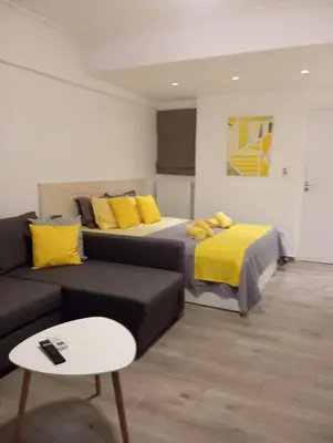 a bedroom with a bed and a couch with yellow pillows at Kolonaki Luxury backyard Studio in Athens