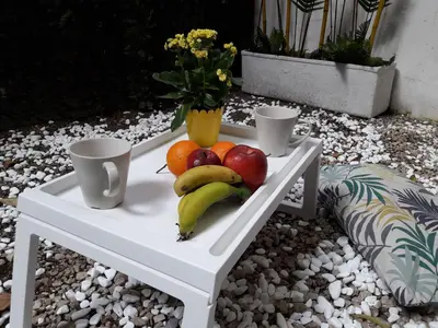 a white table with fruit on it with a vase of flowers at Kolonaki Luxury backyard Studio in Athens