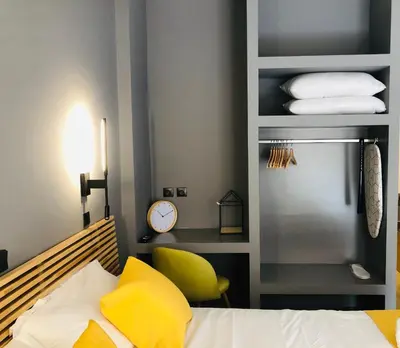 a bedroom with a bed and a yellow chair at Metropolitan Complex Suite 2@faliro in Piraeus