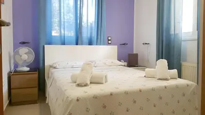 a bedroom with a large white bed with towels on it at Renovated lovely apartment near airport & sea in Porto Rafti
