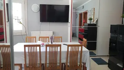 a dining room with a table with chairs and a television at Renovated lovely apartment near airport & sea in Porto Rafti
