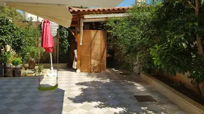 a patio with an umbrella and a building at Renovated lovely apartment near airport & sea in Porto Rafti
