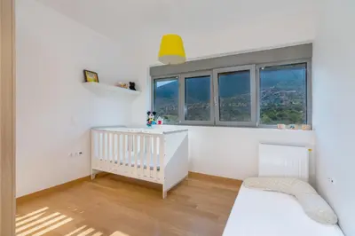 a white nursery with a crib and windows at Your Home2b in Paianía