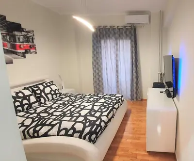 a bedroom with a black and white bed and a television at WHITE HOUSE 30 steps from the Metro station in Athens