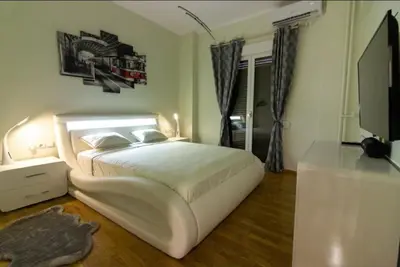 a bedroom with a white bed and a television at WHITE HOUSE 30 steps from the Metro station in Athens