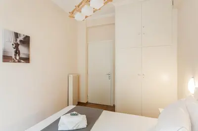 a white bedroom with a bed and a table at La casa di Plaka in Athens