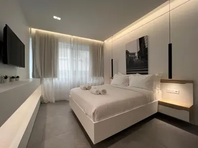 a white bedroom with a large white bed and a window at The Dazzling Glimpse Acropolis Suites in Athens