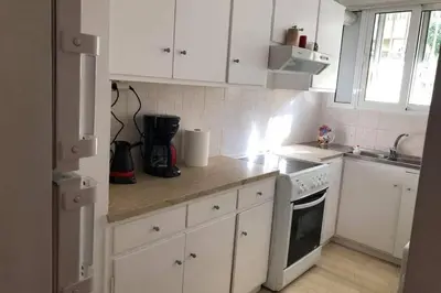 a kitchen with white cabinets and a stove top oven at Cosy & Functional pied-à-terre in Athens