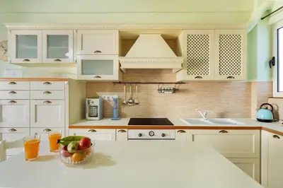 a kitchen with white cabinets and a bowl of fruit on a counter at Bright, Calming Retreat With a Balcony Near Metro! in Athens