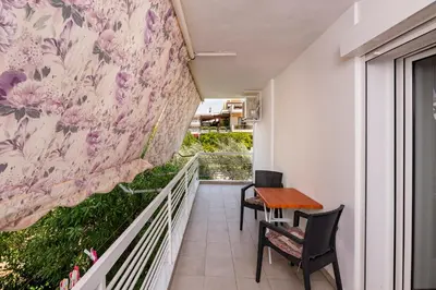 a balcony with a table and chairs and a wall with flowers at Beautifully renovated flat in superb location in Athens
