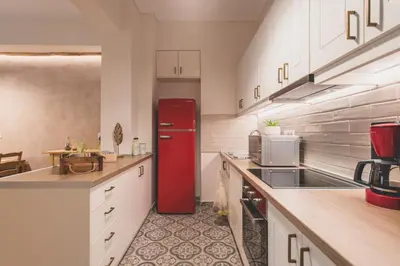 a red refrigerator in a kitchen with white cabinets at 90m2 Luxury Apartment in the Heart of Athens - Living Stone Sunstone in Athens