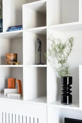 a white book shelf with a vase of flowers at Iconic 1BR Apartment in Koukaki by UPSTREET in Athens