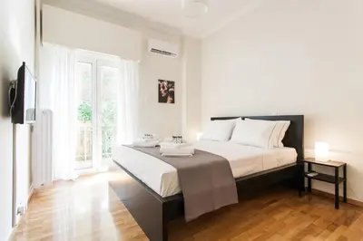 a bedroom with a bed with white sheets and a window at La maison de Philopappou in Athens