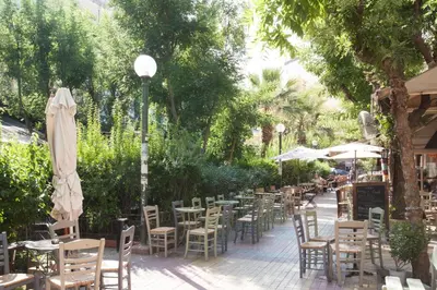 an outdoor restaurant with tables and chairs and umbrellas at La maison de Philopappou in Athens