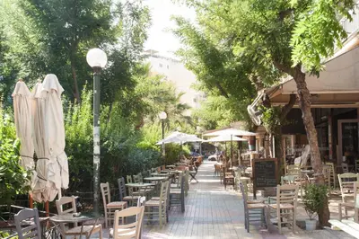 a street with tables and chairs and umbrellas at La maison de Philopappou in Athens