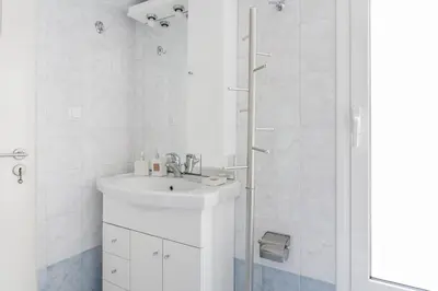 a white bathroom with a sink and a shower at La maison de Philopappou in Athens