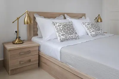 a bed with white pillows and a lamp on a night stand at Polytimon, an Athenian neoclassical apartment in Athens