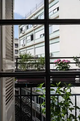a view from a window of a balcony with flowers at Polytimon, an Athenian neoclassical apartment in Athens