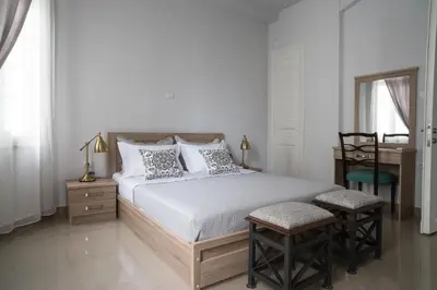 a bedroom with a bed with two chairs and a table at Polytimon, an Athenian neoclassical apartment in Athens
