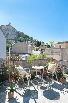 a patio with two chairs and a table and some plants at Acropolis Crib Spot in Athens