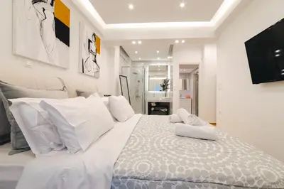 a white bedroom with a large bed with white pillows at D9 center of Glyfada in Athens