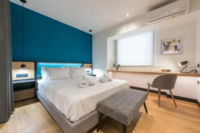 a bedroom with a bed and a desk and a chair at Brand New Ermou Veni Apartment in Athens