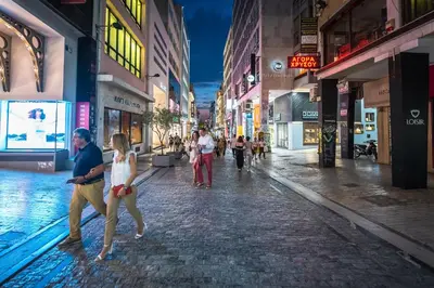 a group of people walking down a street at night at Brand New Ermou Veni Apartment in Athens