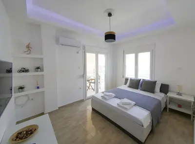 a white bedroom with a large bed and a bathroom at Lux Sea Apartment - Porto Rafti in Porto Rafti
