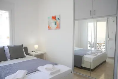 a white bedroom with a bed and a mirror at Lux Sea Apartment - Porto Rafti in Porto Rafti