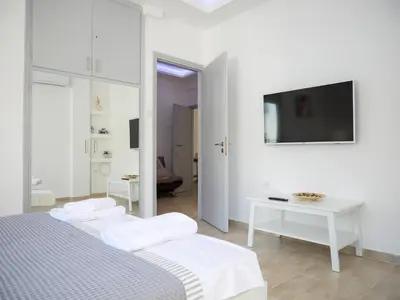 a white bedroom with two beds and a tv at Lux Sea Apartment - Porto Rafti in Porto Rafti