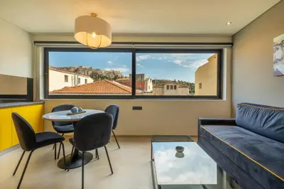 a living room with a couch and a table and a large window at Muse Urban Suites in Athens