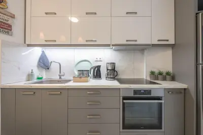 a kitchen with white cabinets and a sink at Earthy Green House in Athens